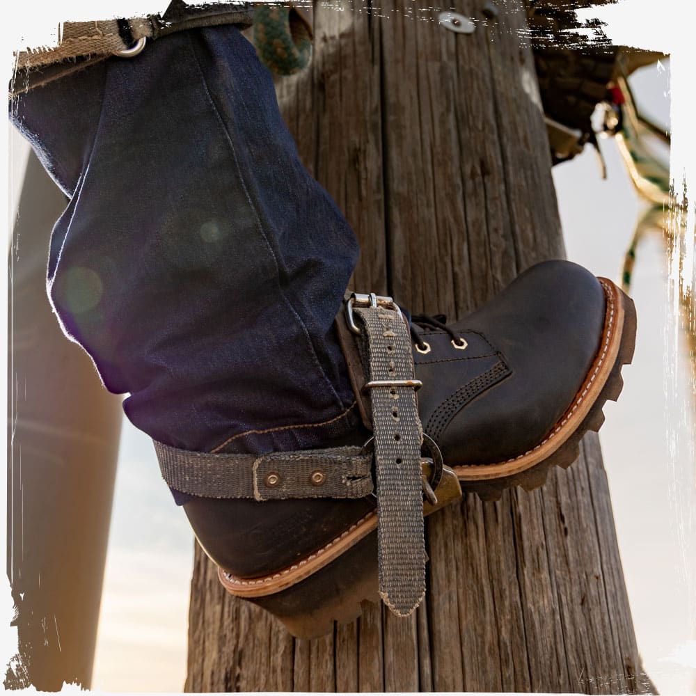 A man wearing The Baldor 8" Steel Toe Logger in black oiled while climbing a pole.
