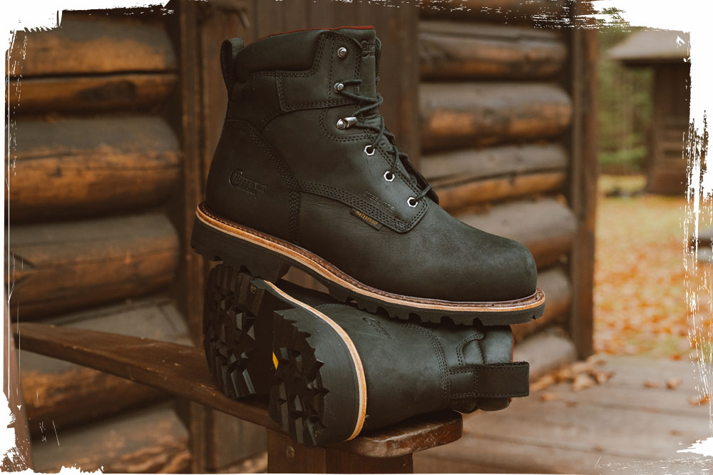 The Super Dna 6" Waterproof Steel Toe Lace-Up work boot in Charcoal (black) next to a log cabin.