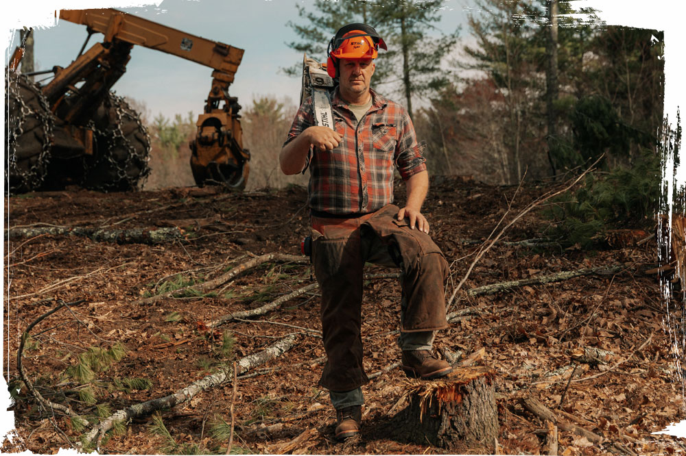 A man wearing Super Logger 9" Waterproof Insulated Steel Toe in aged brown while standing in the forest.
