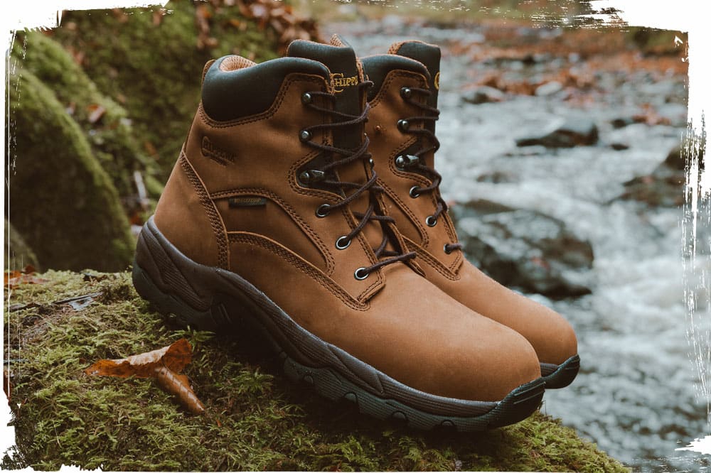 The Chippewa Graeme 6" Waterproof Comp Toe Hiker in brown sitting on a mossy rock near a stream.