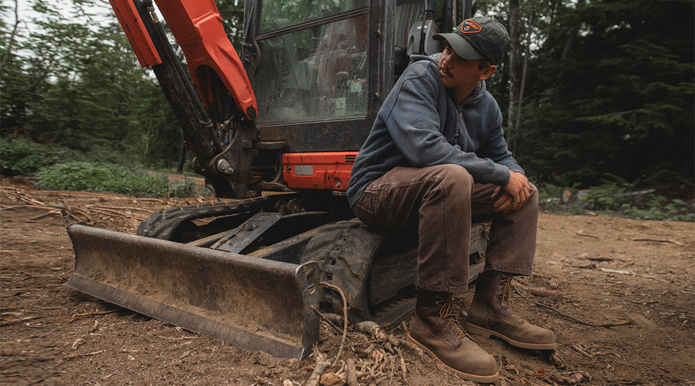 Un hombre sentado en un tractor y usando botas de trabajo Chippewa.