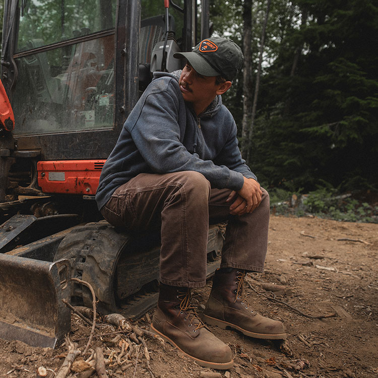 Un hombre sentado en un tractor y usando botas de trabajo Chippewa.