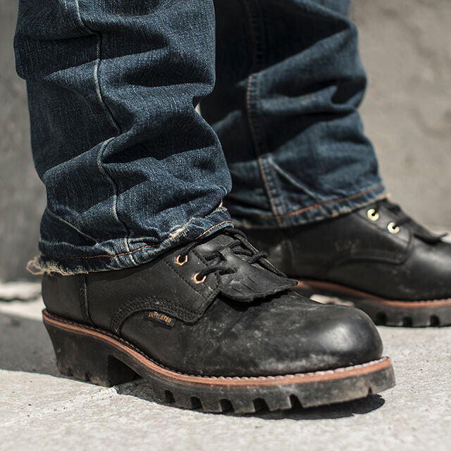 Un hombre llevando las botas Paladin 8" con puntera de acero, aislamiento impermeable, en color negro, de pie sobre concreto.