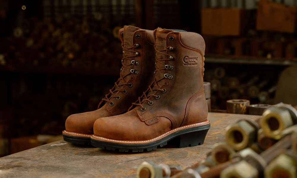 A pair of the Thunderstruck 9" Waterproof Nano Comp Toe Logger in Walnut sitting on a workbench.