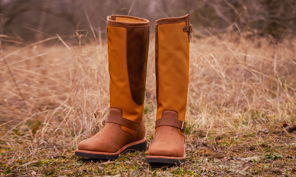A pair of the Cottonwood 17" Snake Boot in Hickory Brown in the grass.